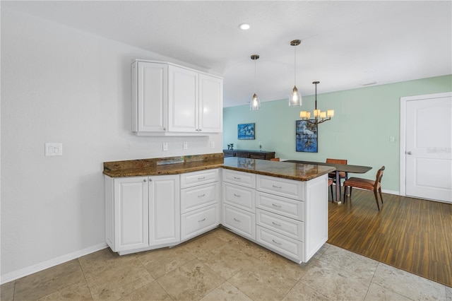 kitchen featuring a chandelier, white cabinets, a peninsula, and baseboards