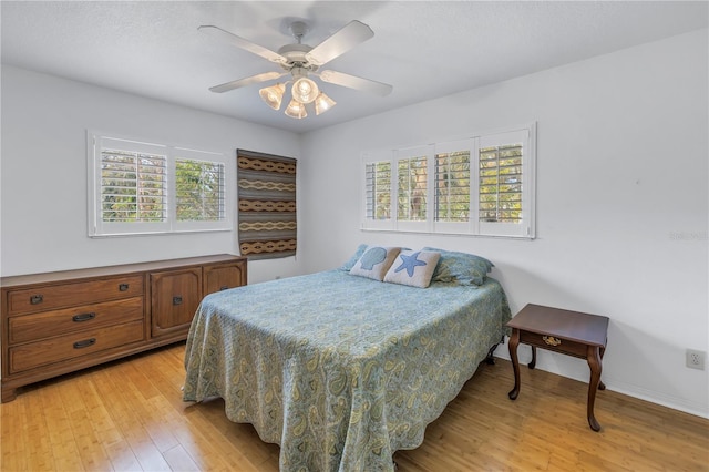 bedroom with light wood-style floors, baseboards, and a ceiling fan