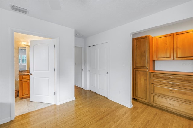 unfurnished bedroom with a closet, visible vents, baseboards, and light wood finished floors