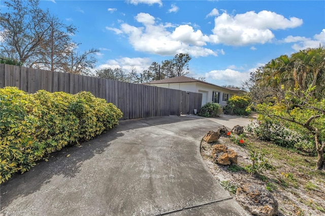 view of side of home featuring driveway and fence