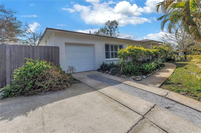 view of front facade with driveway, an attached garage, and fence