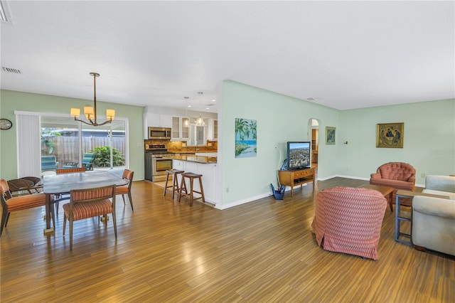 living room featuring dark wood-style floors, baseboards, visible vents, and an inviting chandelier