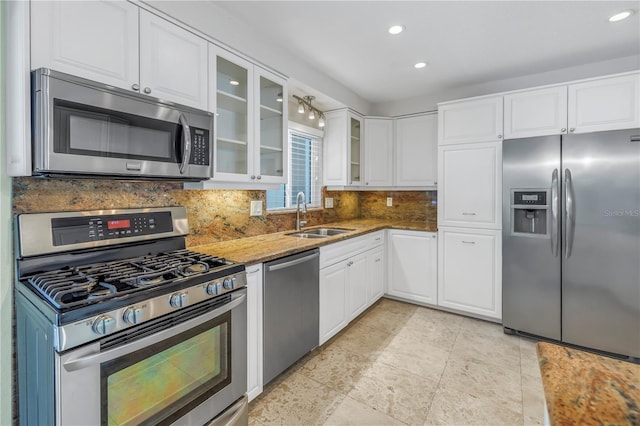 kitchen with stainless steel appliances, a sink, white cabinets, and decorative backsplash