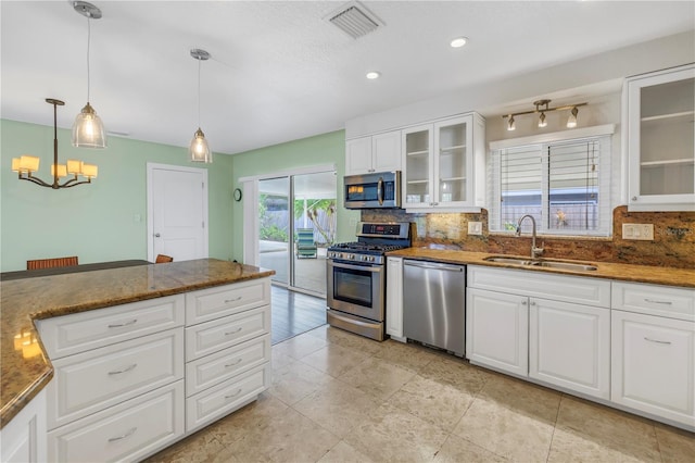 kitchen featuring stainless steel appliances, visible vents, decorative backsplash, white cabinets, and a sink