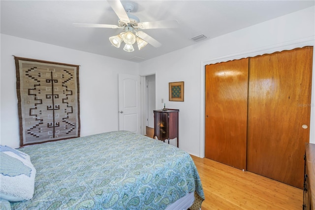 bedroom featuring light wood finished floors, a closet, visible vents, and a ceiling fan