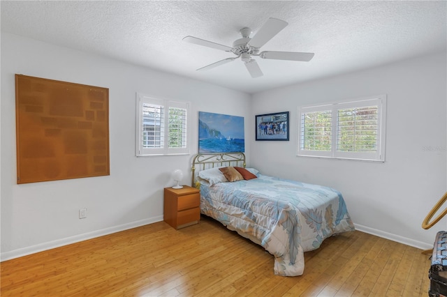 bedroom with light wood finished floors, ceiling fan, baseboards, and a textured ceiling