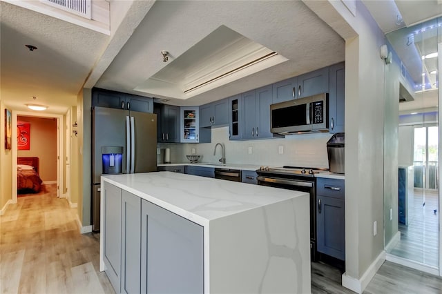7432 Sunshine Skyway Ln S Unit 206, Saint Petersburg, FL 33711 - kitchen featuring tasteful backsplash, light stone countertops, black appliances, a raised ceiling, and a kitchen island