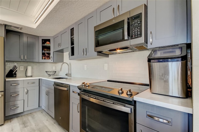 7432 Sunshine Skyway Ln S Unit 206, Saint Petersburg, FL 33711 - kitchen featuring gray cabinetry, stainless steel appliances, a textured ceiling, light hardwood / wood-style floors, and sink
