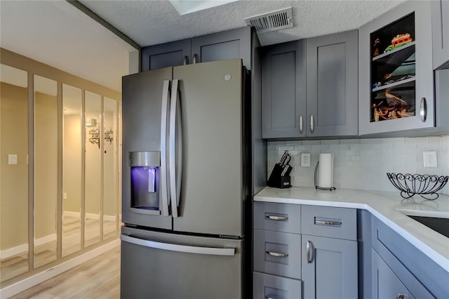 7432 Sunshine Skyway Ln S Unit 206, Saint Petersburg, FL 33711 - kitchen with a textured ceiling, light hardwood / wood-style floors, stainless steel fridge, and decorative backsplash