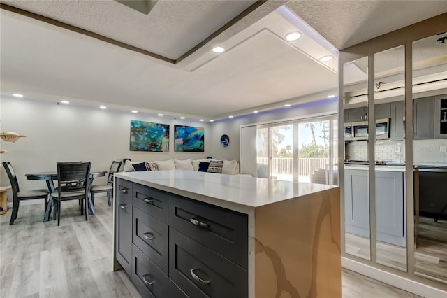 7432 Sunshine Skyway Ln S Unit 206, Saint Petersburg, FL 33711 - kitchen featuring backsplash, a kitchen island, and light hardwood / wood-style floors