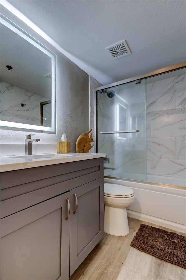 7432 Sunshine Skyway Ln S Unit 206, Saint Petersburg, FL 33711 - full bathroom featuring toilet, a textured ceiling, hardwood / wood-style floors, enclosed tub / shower combo, and vanity