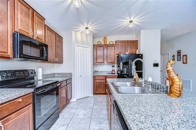 kitchen with light tile patterned flooring, sink, light stone counters, a textured ceiling, and black appliances