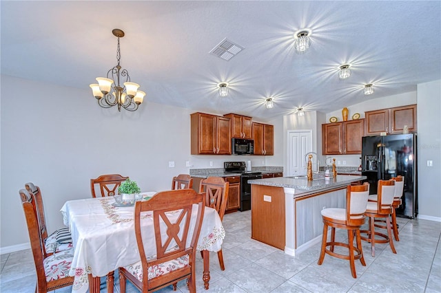 kitchen with decorative light fixtures, sink, black appliances, a center island with sink, and an inviting chandelier