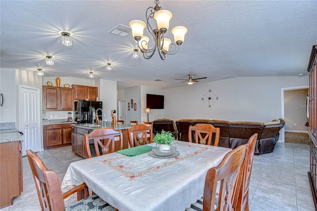 tiled dining space with ceiling fan with notable chandelier, sink, and a textured ceiling