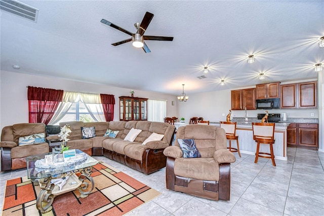 living room with lofted ceiling, light tile patterned floors, ceiling fan with notable chandelier, and a textured ceiling