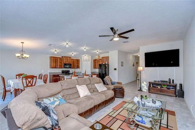 living room with light tile patterned floors, ceiling fan with notable chandelier, and a textured ceiling