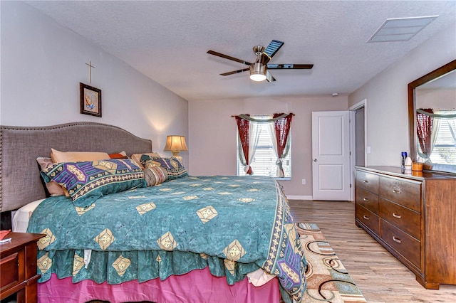 bedroom with ceiling fan, light hardwood / wood-style floors, and a textured ceiling