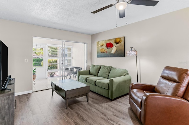 living room featuring a textured ceiling, wood finished floors, baseboards, and ceiling fan