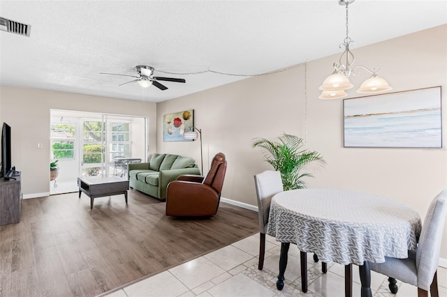 dining space featuring visible vents, baseboards, ceiling fan, wood finished floors, and a textured ceiling