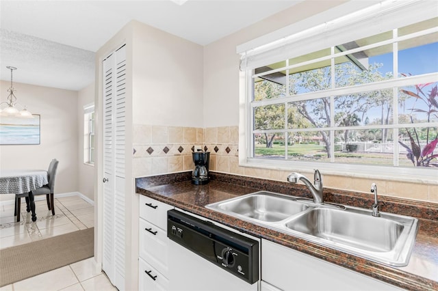 kitchen with dishwashing machine, light tile patterned floors, a sink, white cabinetry, and dark countertops