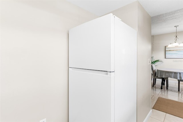 kitchen with light tile patterned floors, a textured ceiling, and freestanding refrigerator