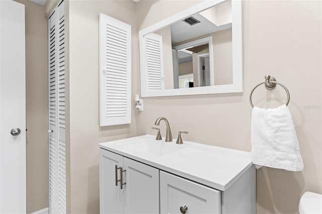 bathroom featuring visible vents, toilet, and vanity