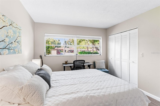 bedroom featuring a closet, a textured ceiling, baseboards, and wood finished floors