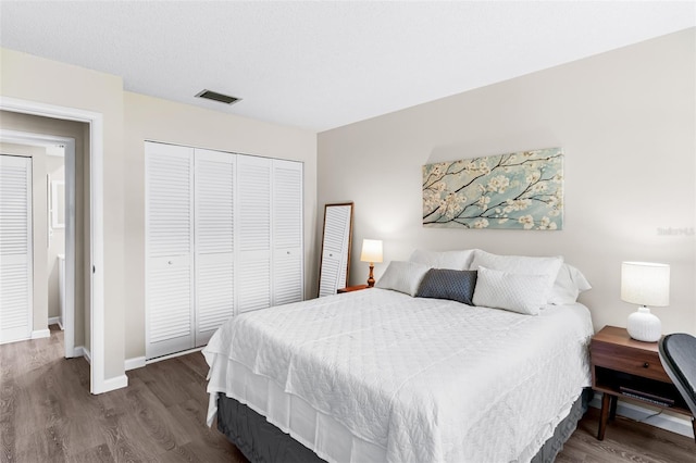 bedroom with a closet, baseboards, visible vents, and wood finished floors