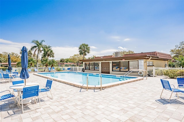 community pool with a patio and fence