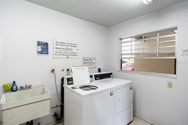 common laundry area featuring a sink, a textured ceiling, and separate washer and dryer