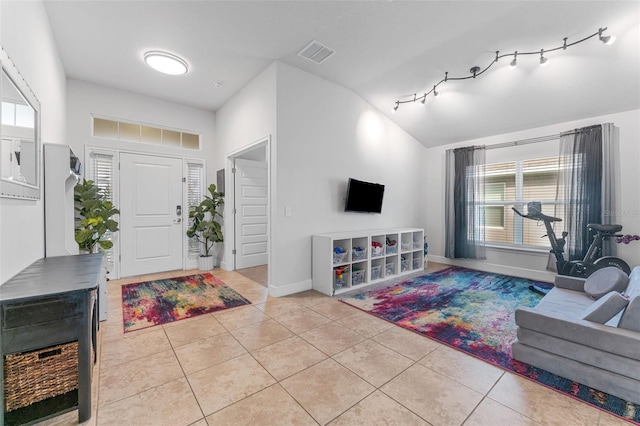 living room featuring light tile patterned floors, vaulted ceiling, and rail lighting