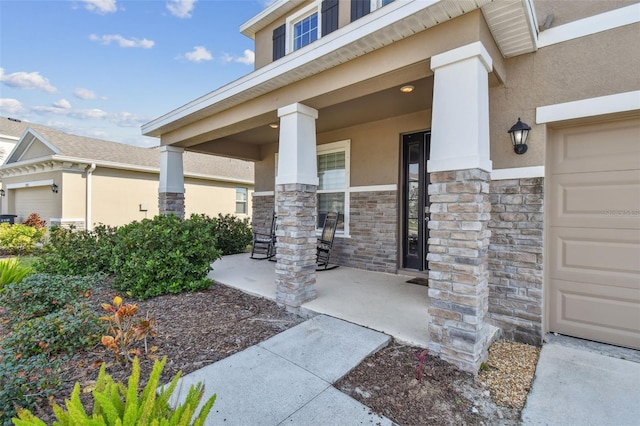 view of exterior entry with a garage and a porch