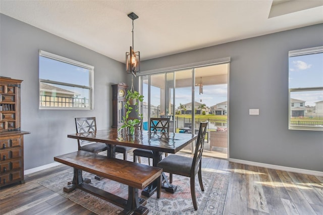 dining room with a water view, dark wood-type flooring, and a wealth of natural light