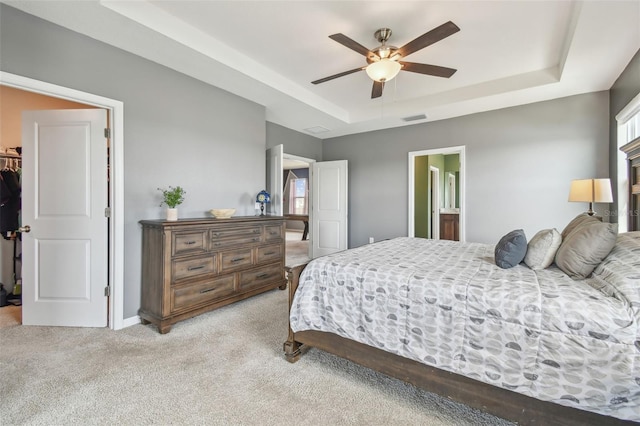 carpeted bedroom featuring ceiling fan, a spacious closet, a raised ceiling, and multiple windows