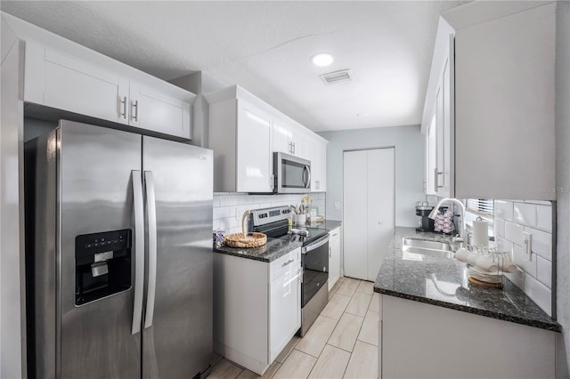 9169 Robin Rd, Seminole, FL 33777 - kitchen with sink, white cabinetry, tasteful backsplash, dark stone countertops, and appliances with stainless steel finishes