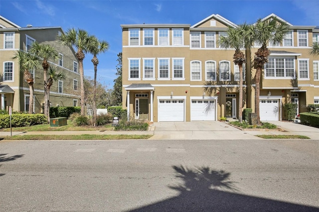 townhome / multi-family property featuring driveway, an attached garage, and stucco siding