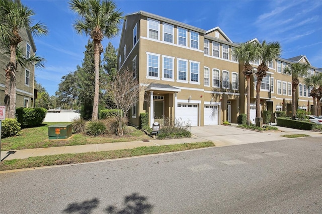 multi unit property featuring driveway, an attached garage, and stucco siding