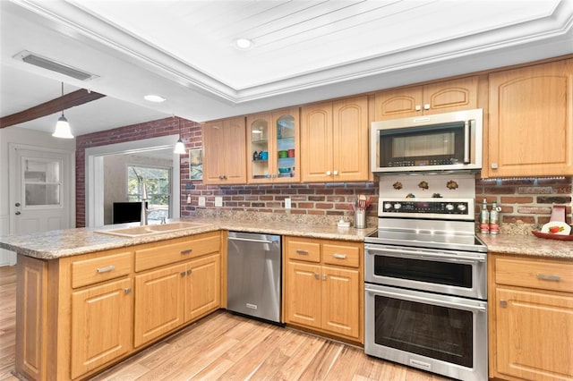 kitchen with stainless steel appliances, light stone countertops, decorative backsplash, light hardwood / wood-style floors, and kitchen peninsula