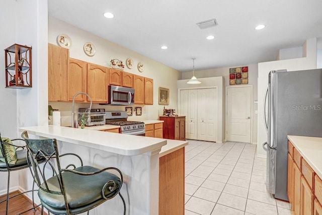 kitchen with hanging light fixtures, stainless steel appliances, a breakfast bar, and kitchen peninsula