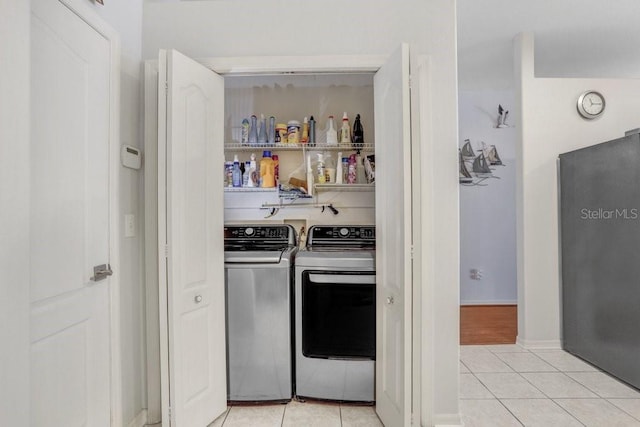 clothes washing area with light tile patterned floors and washer and dryer