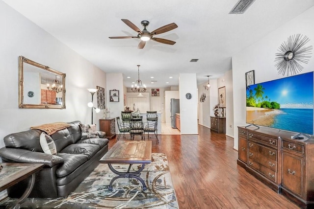 living room with ceiling fan with notable chandelier and hardwood / wood-style floors