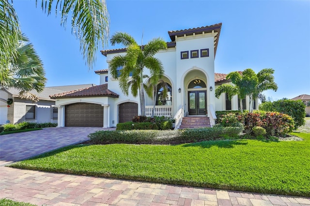 mediterranean / spanish-style house with driveway, french doors, stucco siding, and a tile roof