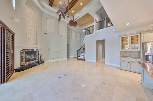 unfurnished living room with a fireplace, visible vents, recessed lighting, a high ceiling, and stairs