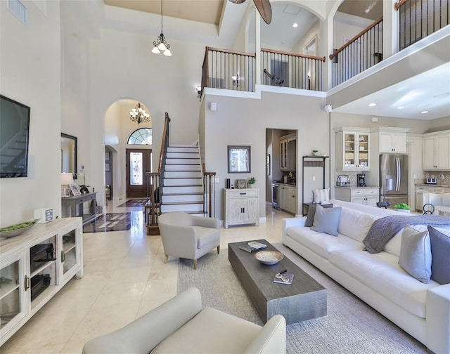 living area featuring visible vents, stairway, arched walkways, and a towering ceiling