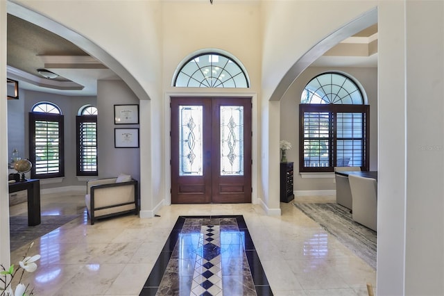 entrance foyer featuring french doors, baseboards, and arched walkways