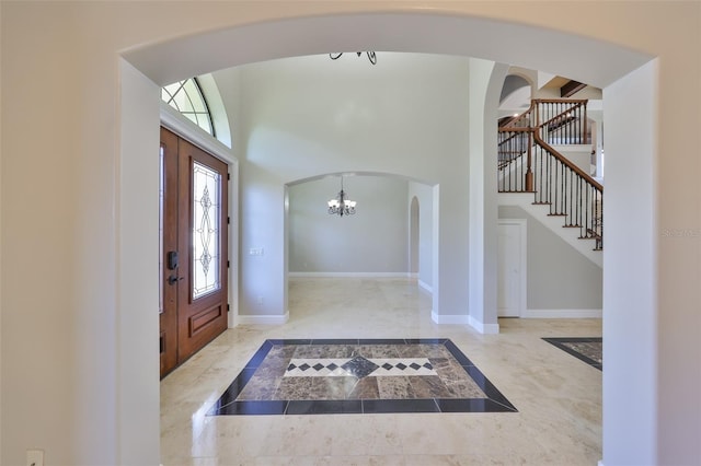 foyer entrance with arched walkways, stairway, a high ceiling, baseboards, and a notable chandelier