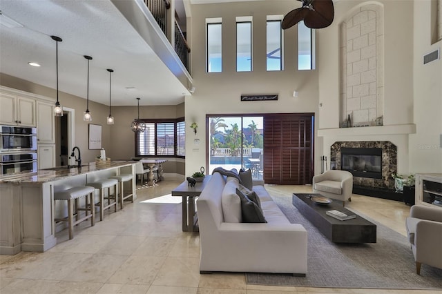 living room with visible vents, baseboards, light tile patterned floors, a high ceiling, and a fireplace