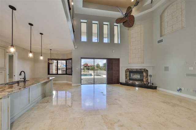 unfurnished living room with baseboards, a high ceiling, marble finish floor, a sink, and a premium fireplace