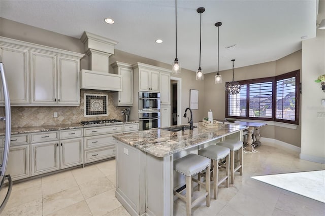 kitchen with light stone countertops, gas stovetop, decorative backsplash, double oven, and a sink