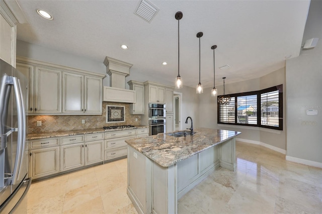 kitchen with appliances with stainless steel finishes, a sink, visible vents, and cream cabinetry